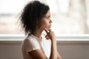 Pensive,Mixed,Race,30s,Woman,Sitting,At,Home,Touch,Chin